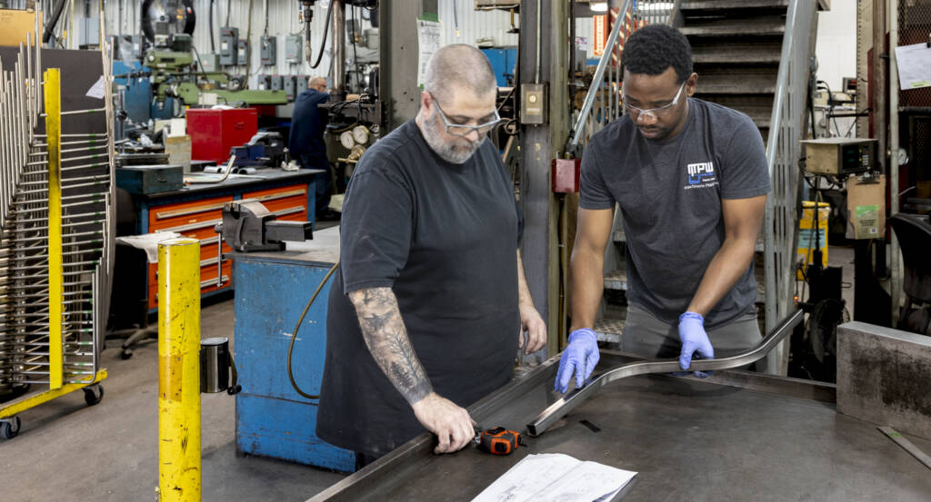 des employés collaborent dans une usine de production métallique